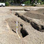 The underground plumbing being backfilled.